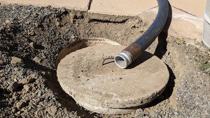 Vacuum hose pumping a septic tank through the access lid during a cleanout